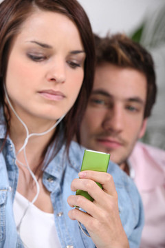 年輕女人聽MP3播放器旁邊的男友