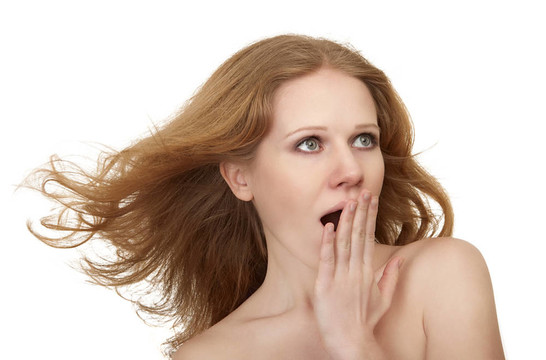 美麗令人驚訝的女孩與流動的頭發(fā)覆蓋張開的嘴與她的手在震驚孤立的白色背景