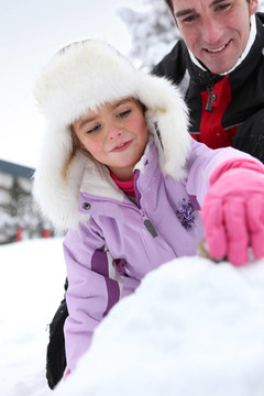 父親和女兒在雪地里玩