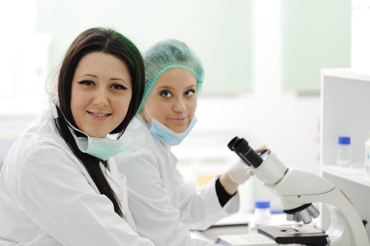 兩名女性科學家在實驗室用顯微鏡工作