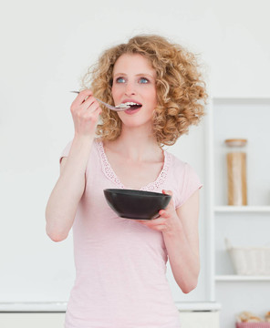 漂亮的金發(fā)女人在廚房里吃一碗麥片