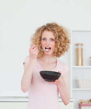 漂亮的金發(fā)女人在廚房里吃一碗麥片
