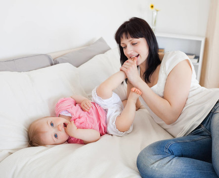 漂亮的黑發(fā)女玩她的寶寶躺在她的公寓床