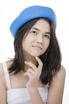 漂亮的戴著藍(lán)色帽子的年輕少女；用若有所思的表情仰望；手指觸摸下巴。