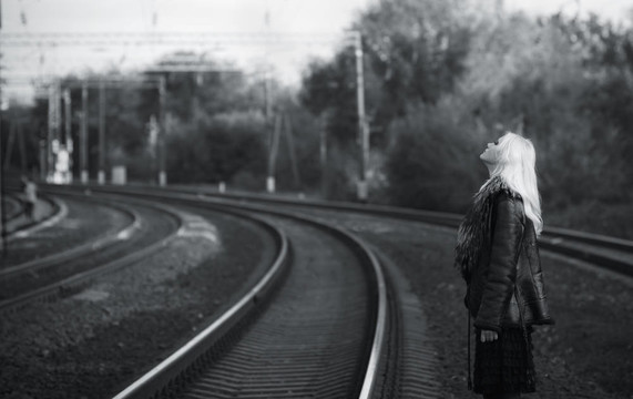 美麗的少女等待火車在鐵軌上的肖像。黑色和白色