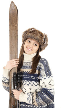 冬季的帽子和毛衣抱著舊的木制滑雪板的少女微笑的畫像；白色背景