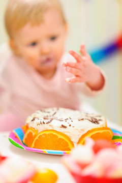 特寫在生日蛋糕和背景匿名吃抹上嬰兒