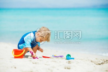 在热带海滩玩沙滩玩具的男孩