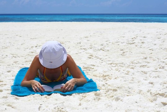 年輕婦女正在海灘上看這本書