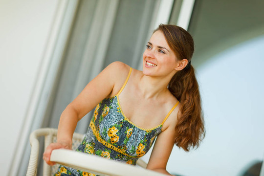 快乐的女人坐在阳台上看着角落