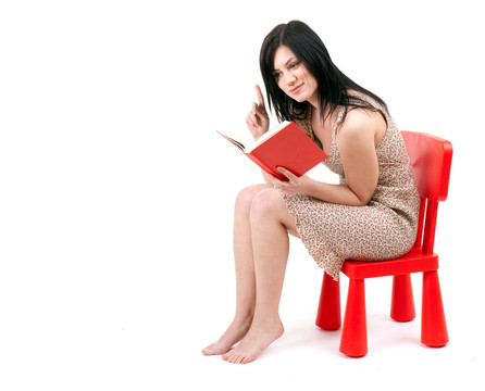 坐在紅色的；孩子的椅子年輕女子讀書