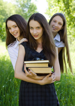 三快乐的学生女孩在公园里看书
