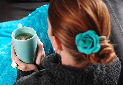 沙發(fā)上的女人用毯子和一杯茶