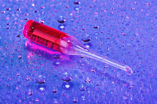 在抽象的水滴背景紅色安瓿；宏觀