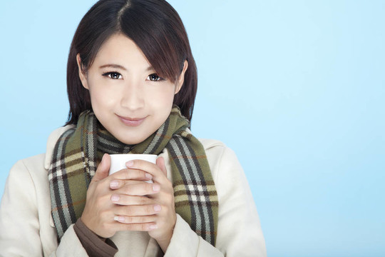 漂亮的女人穿著冬天的衣服，拿著咖啡杯