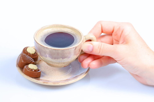 果仁巧克力；杯；黑咖啡和女性手上白色