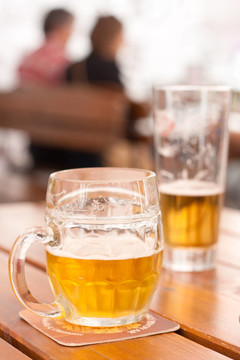 啤酒飲用：一個半填充啤酒杯在城市餐廳戶外活動桌上特寫