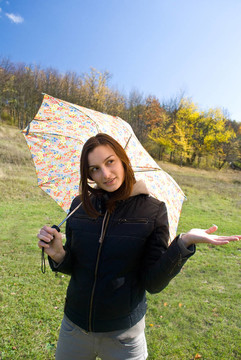 畫面中一位年輕快樂微笑的女孩站在雨中帶著傘