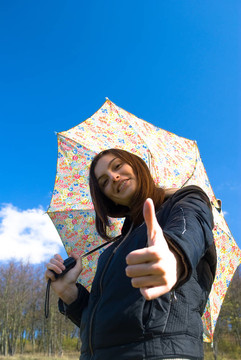 畫面中一位年輕快樂微笑的女孩站在雨中帶著傘