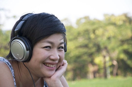 美麗的亞洲女人在公園聽音樂