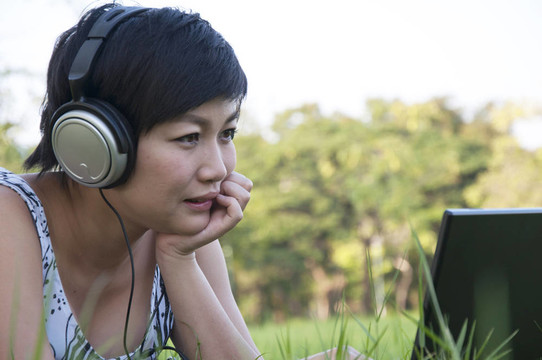 美麗的亞洲女人在公園聽音樂