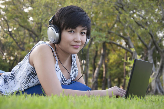 美麗的亞洲女人在公園聽音樂