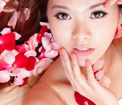 女孩微笑和觸摸面與紅玫瑰