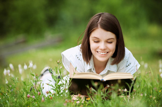 年輕女子躺在草地上看書