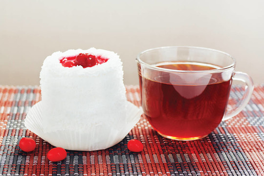 一杯茶和奶油蛋糕與櫻桃在竹桌布仍然生活