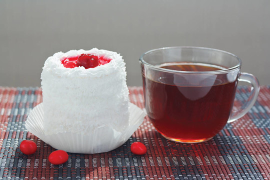 一杯茶和奶油蛋糕與櫻桃在竹桌布仍然生活