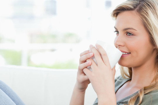 女人笑著用杯子把嘴唇和膝蓋舉起來(lái)