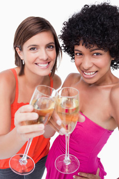 年輕的微笑的女人無比他們的白葡萄酒杯