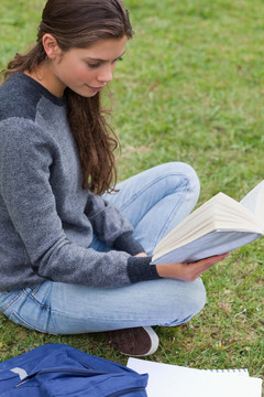 悠閑的小女孩坐在草地上看書