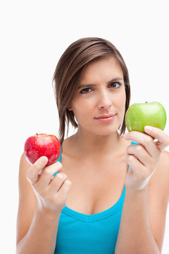 严肃的少女拿着一个绿色和一个红苹果