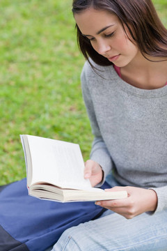 認真的小女孩坐在草地上看書