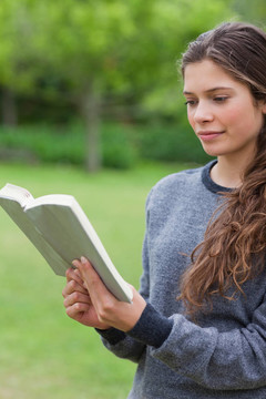 年輕輕松的女孩在公園里看書
