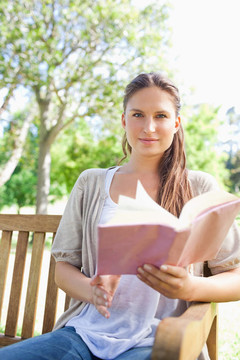 女人坐在公園長椅上看書