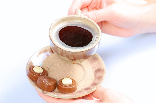 果仁巧克力；杯；黑咖啡和女性手上白色