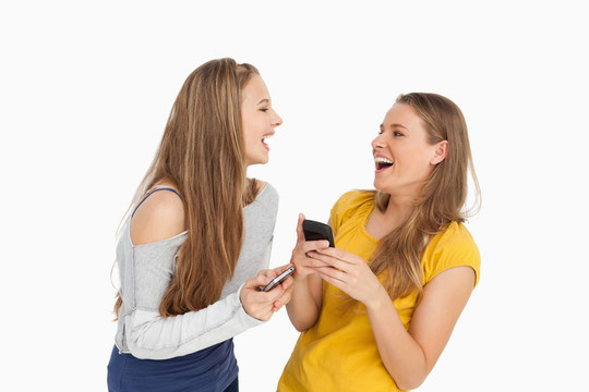 兩個年輕女人邊拿手機邊笑