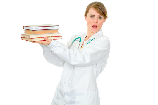 震惊的年轻女医生手里拿着几本医学书籍