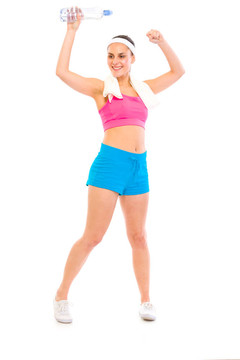 運動女孩用毛巾在她的頭和一瓶水喜悅成功孤立在白色