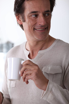 男人笑著喝杯茶。