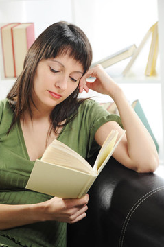 一本書的年輕女人女人肖像；書架上的背景