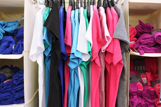 五彩休閑服裝商店的品種；T恤衫掛在衣架，卷成卷