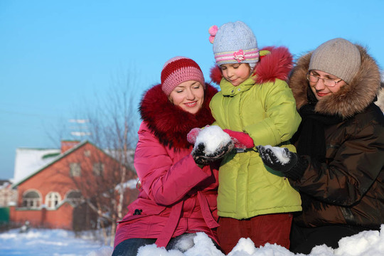 爸爸媽媽在冬天給女兒在戶外做雪球