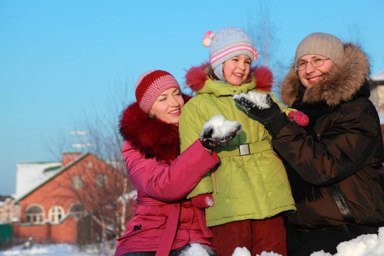 爸爸媽媽在冬天給女兒在戶外做雪球，爸爸媽媽坐在家里