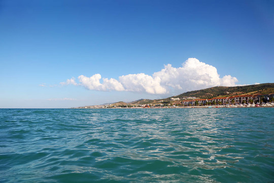 海藍(lán)色的水；遠(yuǎn)處的山和建筑的療養(yǎng)院海灘；