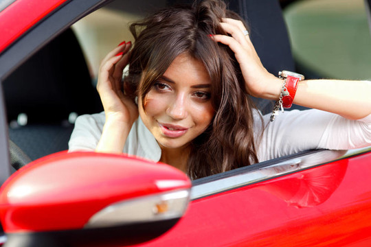 紅色轎車?yán)锏哪贻p漂亮女人