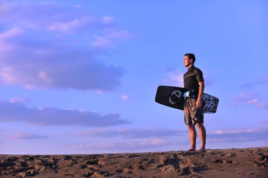 一個年輕人在海灘上的日落kitsurf肖像