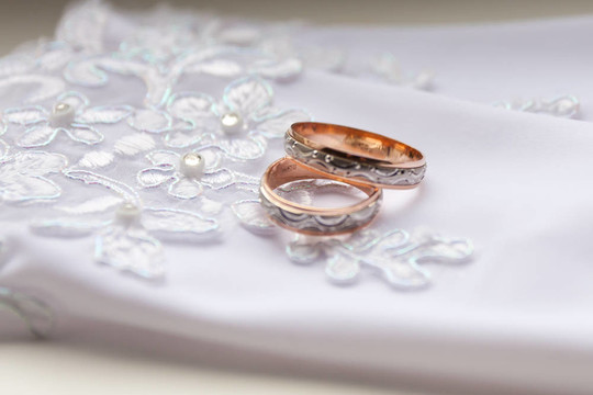白色背景手套上的結(jié)婚戒指。